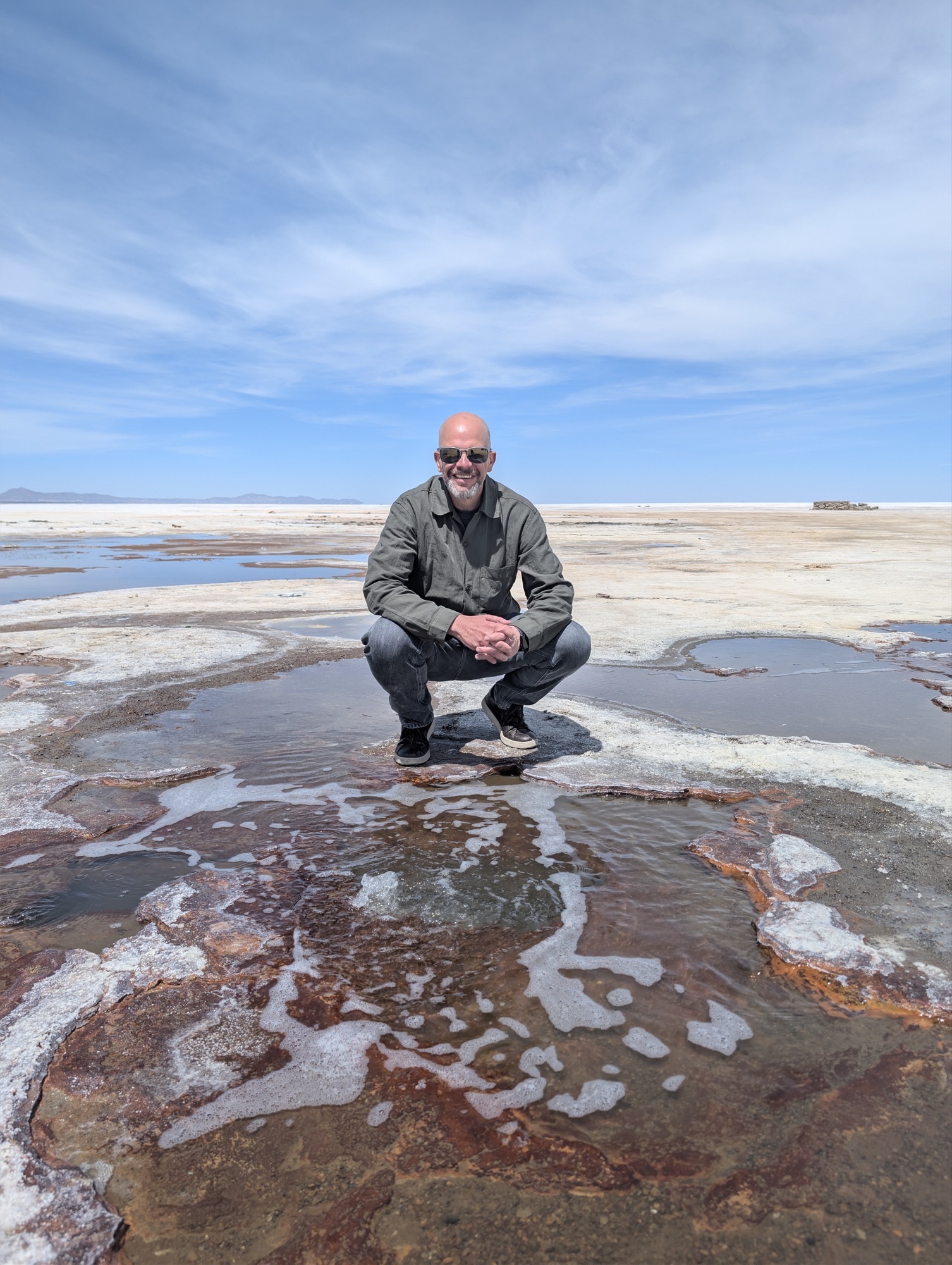 Eduardo crouching at the salt flats between site visits